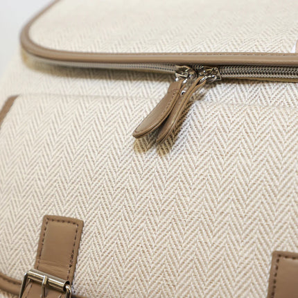 Close-up of a beige textured bag with a zipper and brown leather accents.